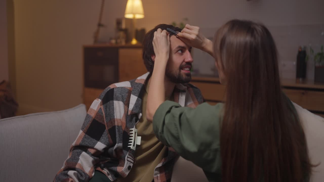 부부가 집에서 서로 머리를 고 있다