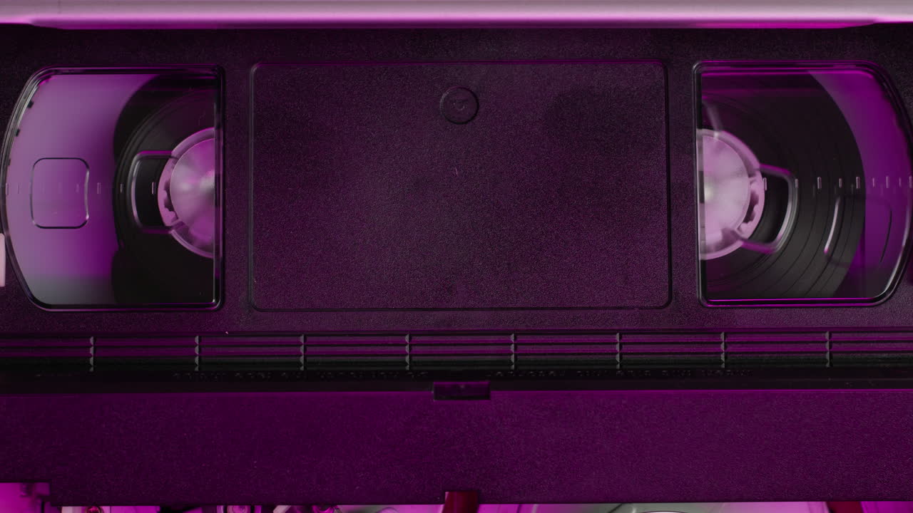 VHS PLAYER, Old video recorder inside in neon pink light close-up, VHS. Retro player in neon blue light, vintage video cassette broadcasting, audio tape.