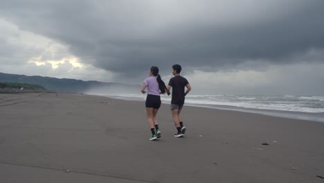 couple running on a beach during stormy weather