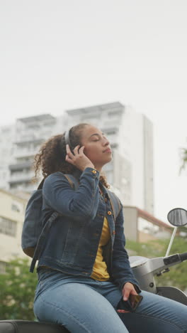 vertical video of happy african american woman wearing headphones in city