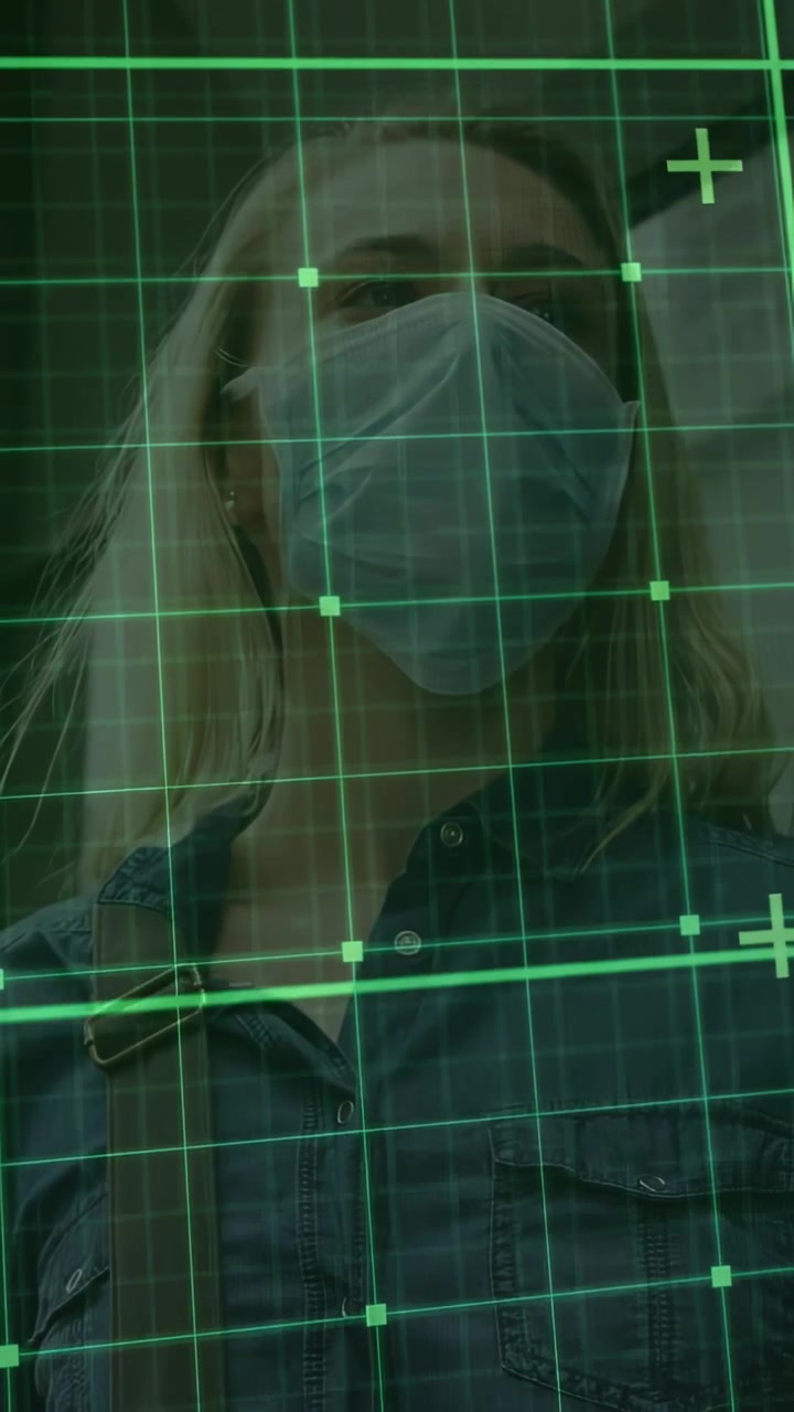 Video verticale: Donna che si gira di profilo dopo il ronzio del telefono, con maschera di tracciamento a griglia verde in transito.
