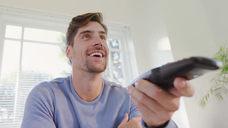 joven riendo mientras ve la televisión en casa 4k 4k