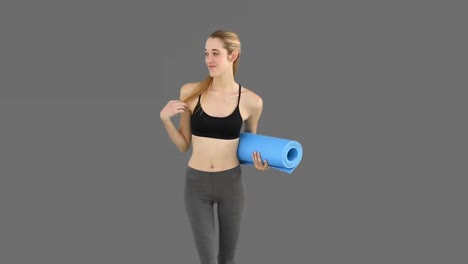 Slim-model-waving-and-holding-exercise-mat