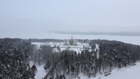 snow-covered pazaislis monastery during snowfall, aerial flying towards view