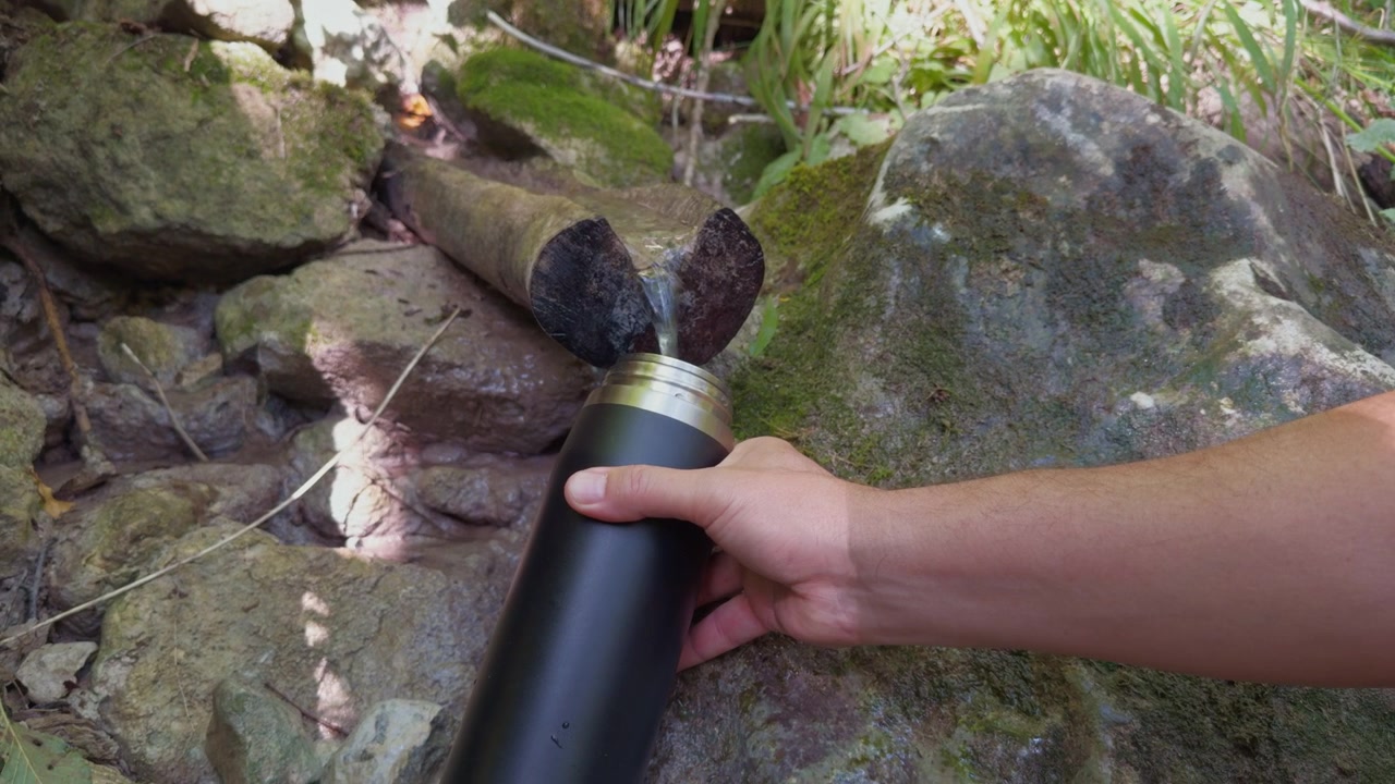 Quenching Thirst with Fresh Cold Water from Mountain Spring into Thermos