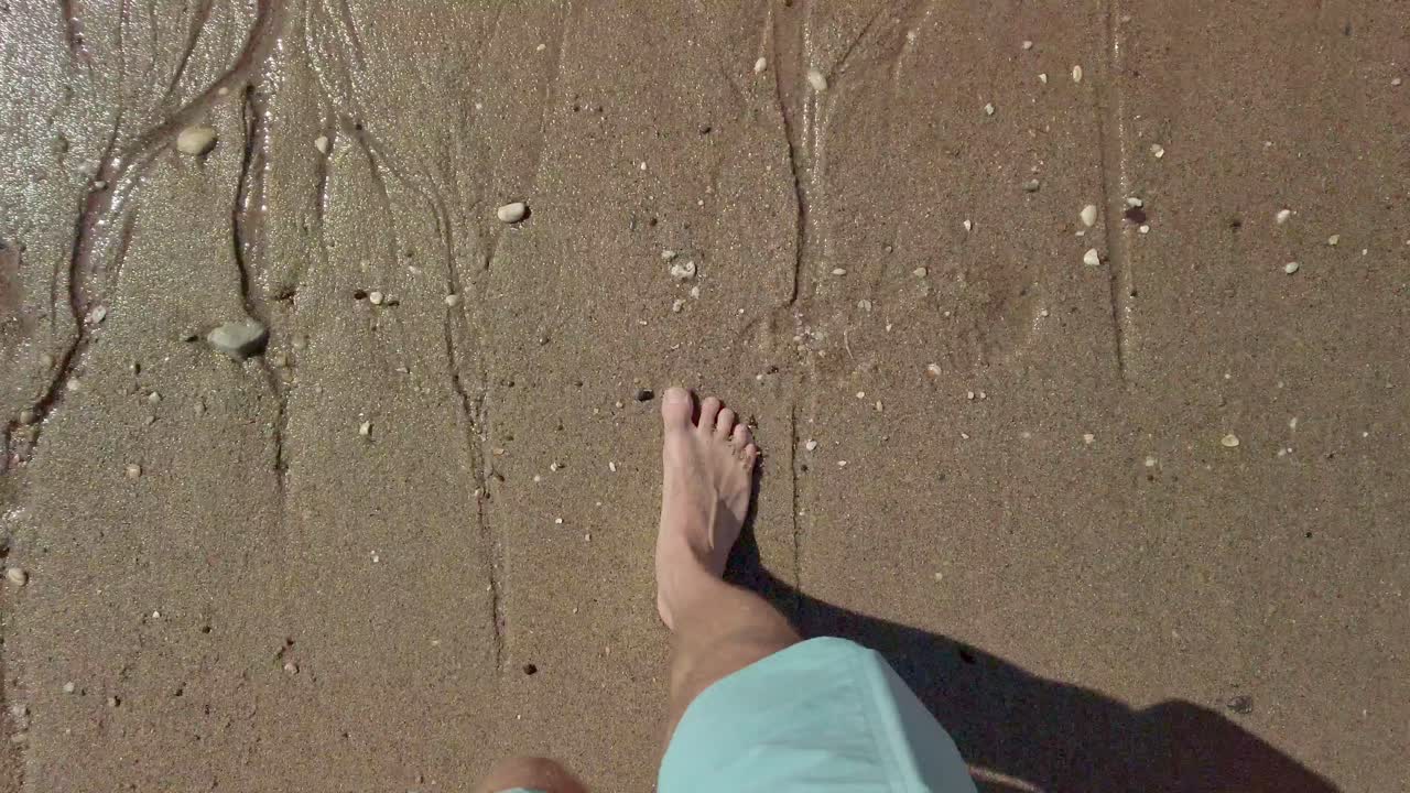 Primo piano dei piedi che camminano sulla sabbia del litorale del Mare del Nord in Zelanda, Paesi Bassi - 4k60