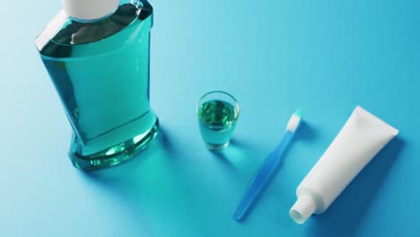 video of close up of toothbrush, paste and mouthwash on blue background