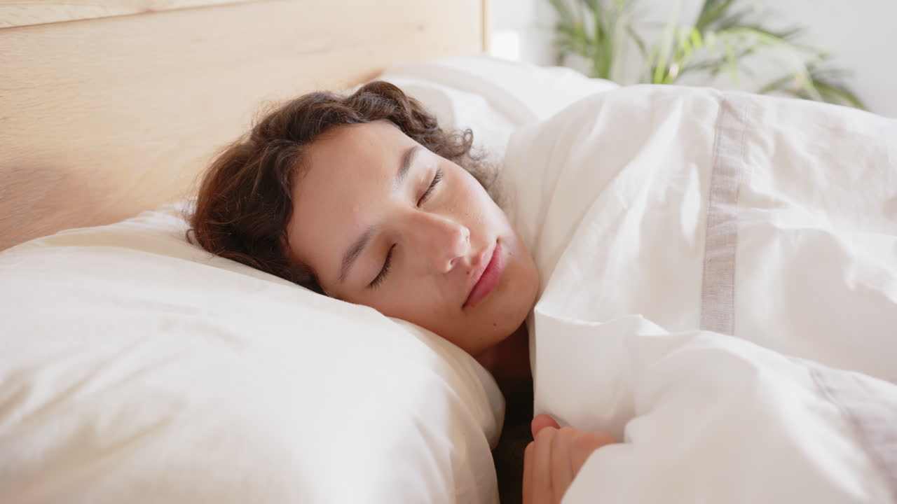 Sleeping peacefully, woman relaxing in bed under white blanket
