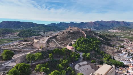 High-quality-filming-with-a-drone-orbiting-the-castle-of-Sagunto-and-its-walls-located-on-a-hill-we-see-the-Roman-amphitheater-with-a-background-of-mountains-and-a-sky-with-clouds-Valencia-Spain