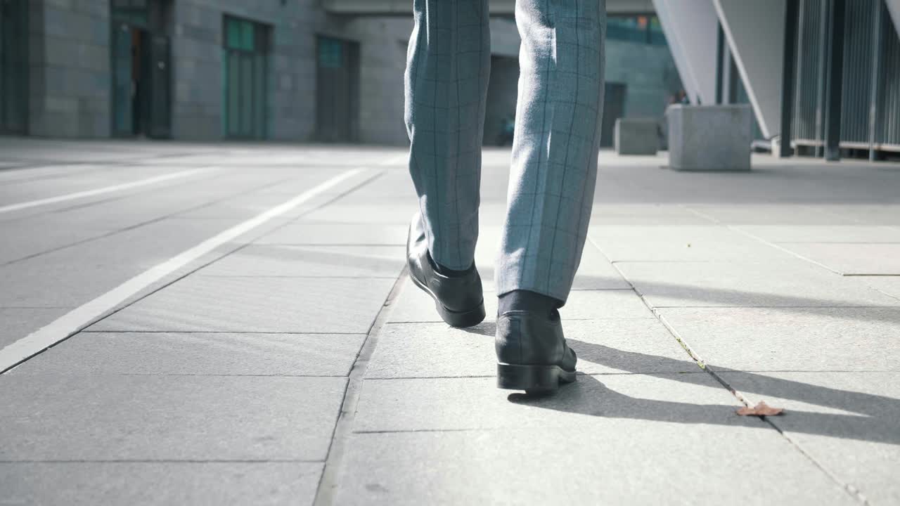 vista trasera pies de hombre de negocios que va a trabajar. vista trasera de hombre confiado empresario en zapatos de cuero y traje formal caminando por el centro cerca de un edificio de oficinas.