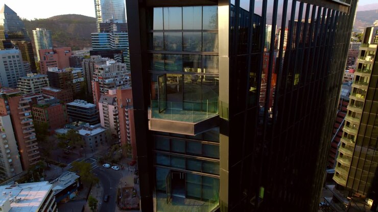 Close-up aéreo de drone de varandas em construção no mercado urbano MUT Santiago do Chile, com a Cordilheira dos Andes e a cidade ao fundo.