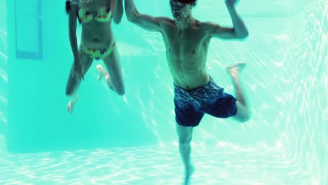 happy couple jumping in swimming pool together