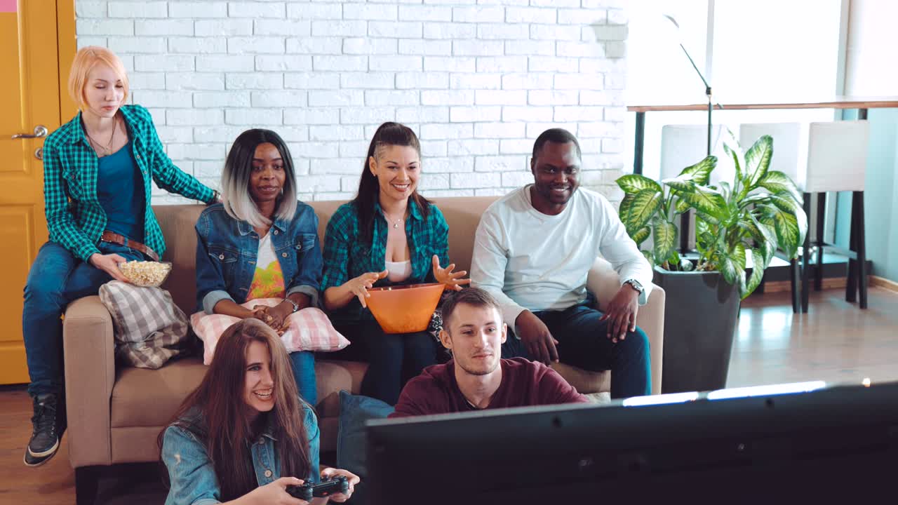 compañía de amigos de diferentes nacionalidades juegan juegos divertidos en la consola. fiesta amistosa