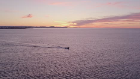 Motorboat-is-cruising-on-calm-sea-during-sunrise-at-Albufeira-Portugal,-aerial