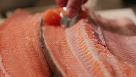 removing excess meat on top of the raw salmon by scraping using spoon