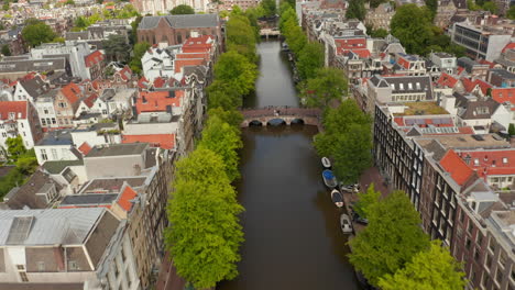 Canal-De-Amsterdam-Con-árboles-Verdes-Y-Tejados-Rojos-Se-Inclina-Lentamente-Hacia-Arriba-Sobre-El-Canal