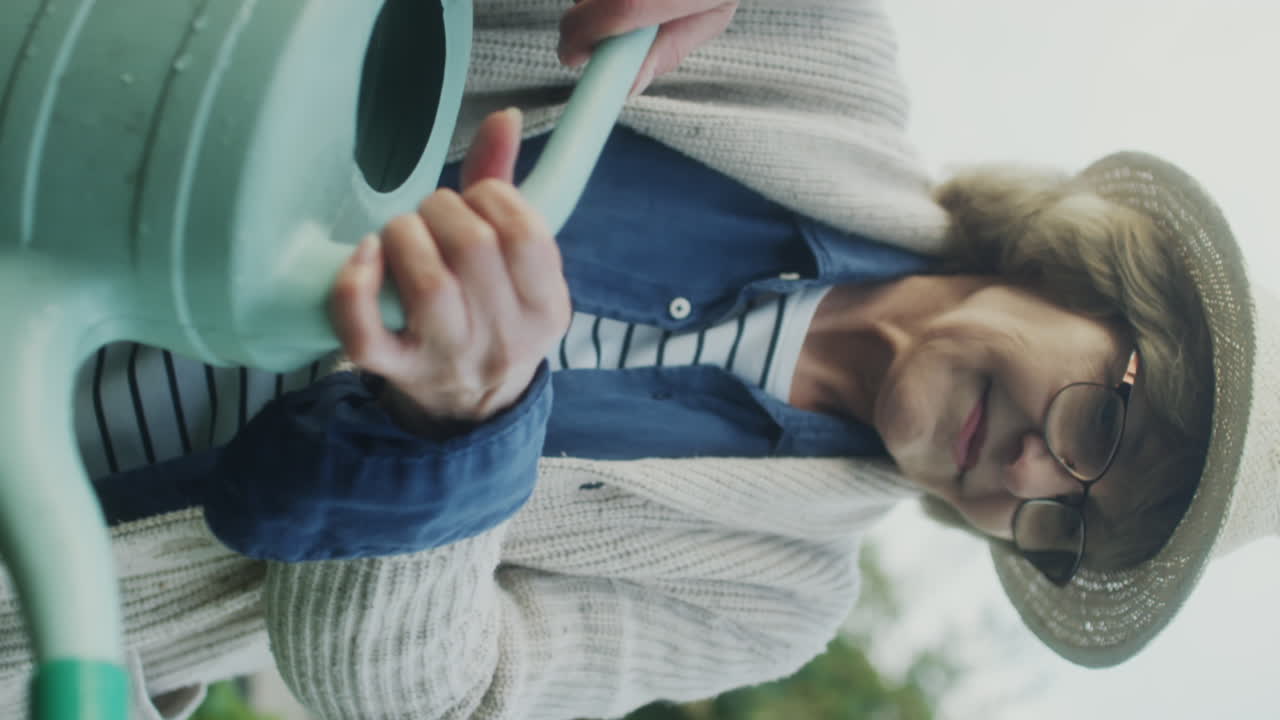 Elderly woman watering plants in the garden