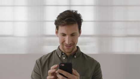 Retrato-De-Un-Joven-Caucásico-Sonriendo-Disfrutando-De-La-Navegación-De-Mensajes-De-Texto-Usando-Tecnología-Móvil-De-Teléfono-Inteligente