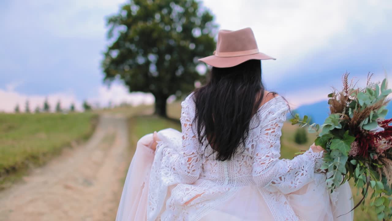 Beautiful bride in the mountains. Pretty young woman wearing long dress walking against mountains view