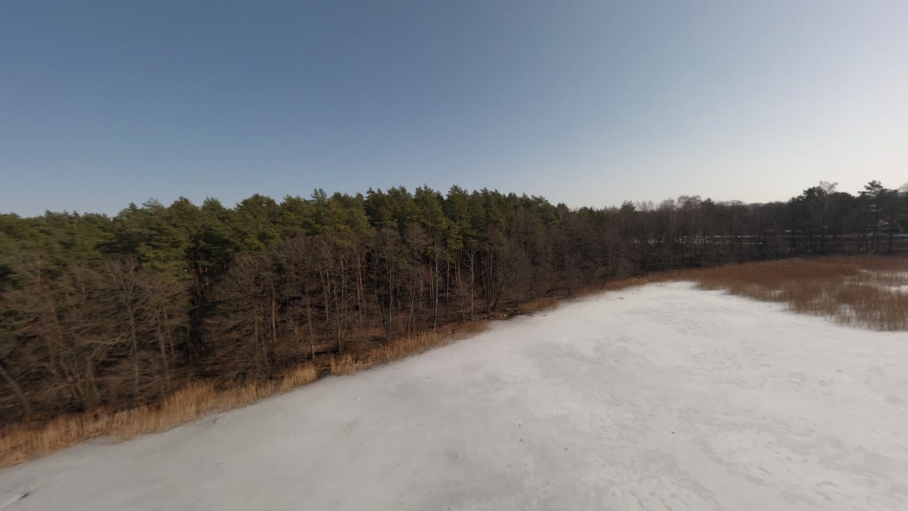 Winter drone flight above icy lake in northern Poland