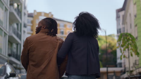 Married-couple-walking-buildings-modern-residential-complex-together-rear-view.