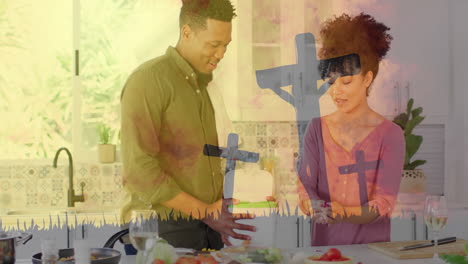 Preparing-food-in-kitchen,-couple-with-cross-animation-over-them