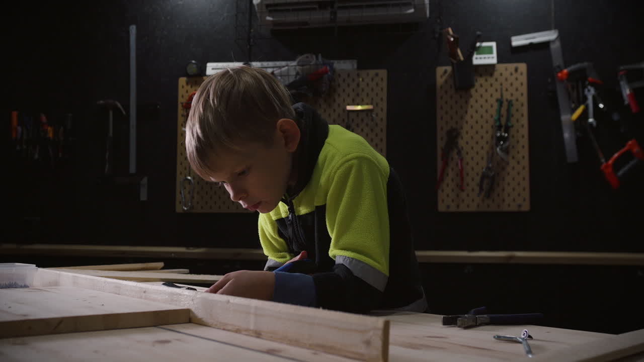 Young boy working on creative woodworking craft in garage, 4k video