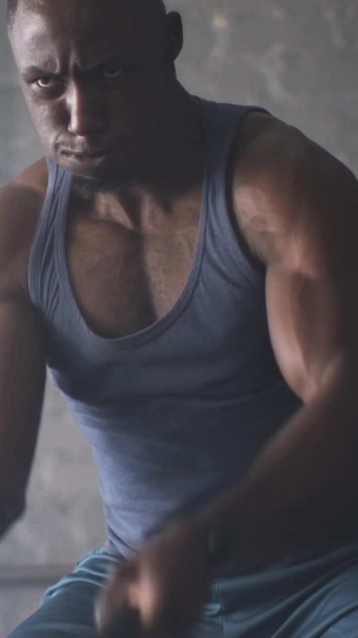 Video verticale: Uomo afroamericano che afferra le battle ropes, oscillando per l'allenamento della forza in palestra.
