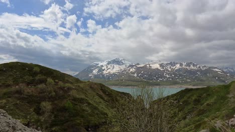 A-breathtaking-timelapse-featuring-snow-capped-mountains,-a-serene-lake,-and-rolling-green-hills-under-a-partly-cloudy-sky,-showcasing-the-beauty-of-nature-in-tranquility