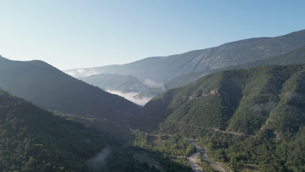Aerial view of majestic French mountains surrounded by lush green valleys under the summer sun.