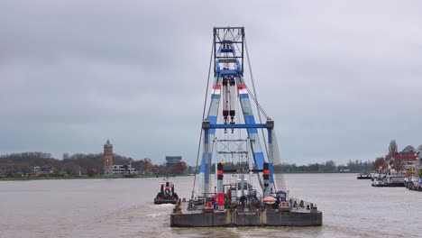 vista trasera, remolcador y grúa flotante juntos navegan por la vía fluvial