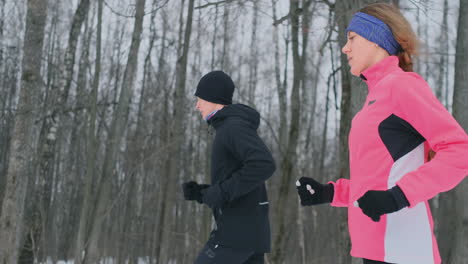 young man and woman on a morning run in the winter forest. a woman in a loose jacket a man in a black jacket is running through a winter park. healthy lifestyle happy family.