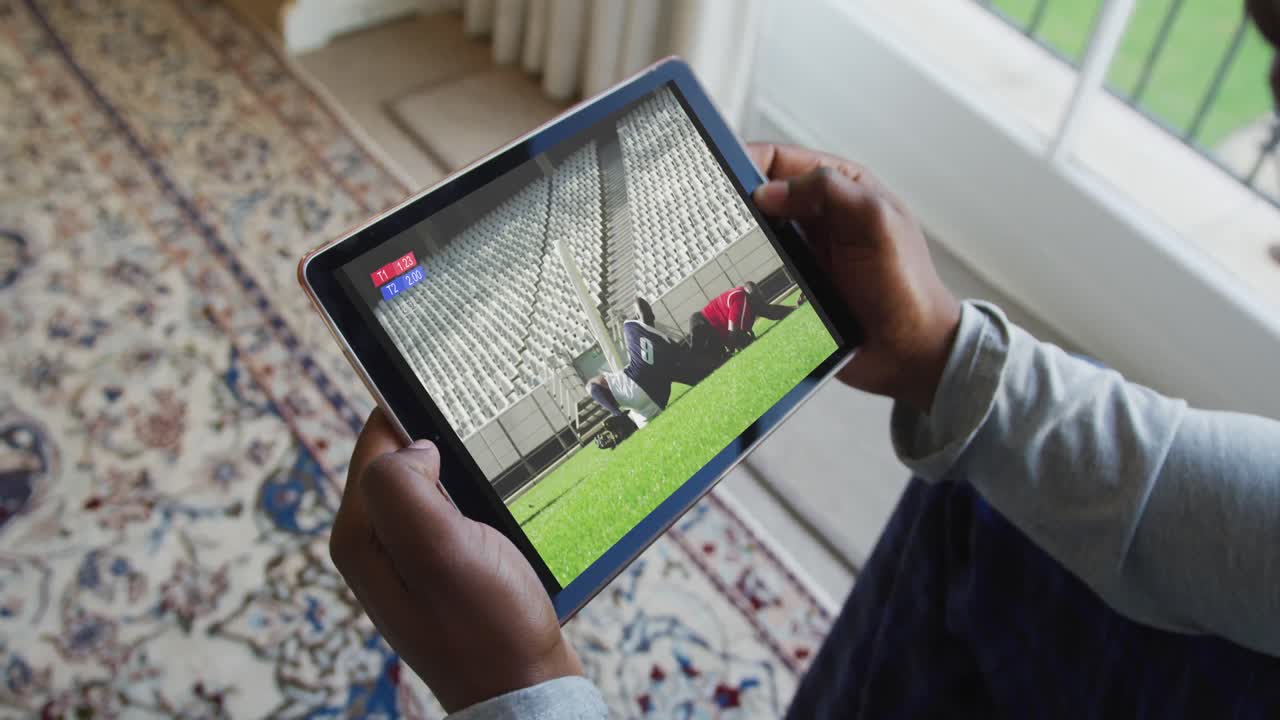 태블릿에서 럭비 경기를 보고 집에 앉아 있는 남자의 복합 사진