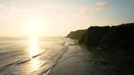 La-Luz-Del-Sol-Dorada-Se-Refleja-En-Las-Cálidas-Aguas-Tropicales,-Las-Olas-Rompiendo-En-La-Playa-De-Melasti,-Al-Sur-De-Bali,-Aérea