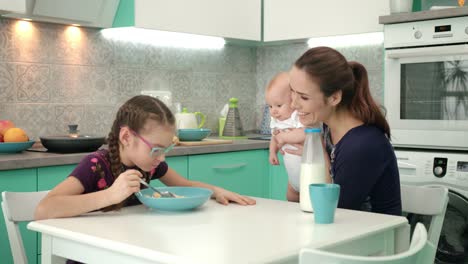 Desayuno-Familiar-Por-La-Mañana.-Chica-Comiendo-Copos-De-Maíz-Con-Leche-En-La-Mesa-De-La-Cocina