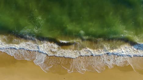 top view of waves breaking into a sandy beach