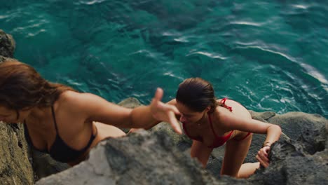 friends climbing up rocks to cliff jump