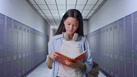 estudiante adolescente asiática con una mochila leyendo un libro y bostezando mientras está de pie en el corredor