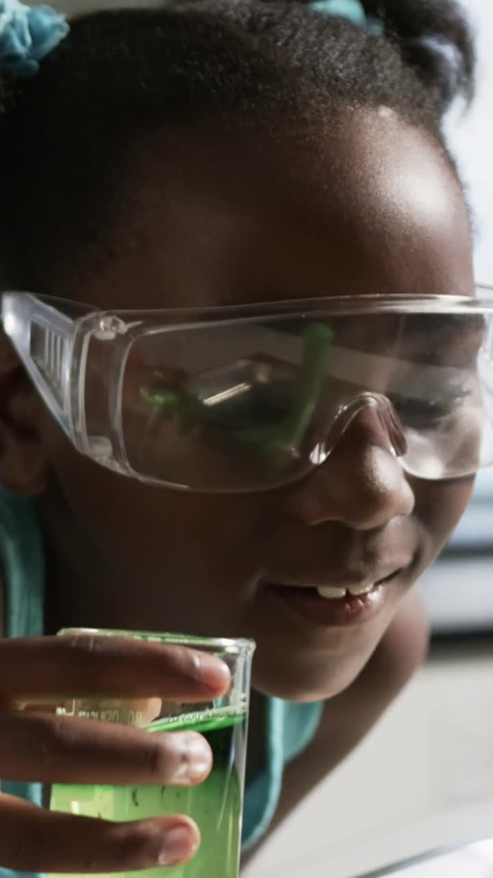 Girl tipping green cup and pouring viscous liquid into sink, inspecting beaker for education