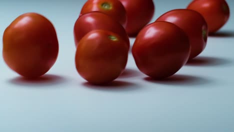 los tomates de cereza caen en una superficie blanca en la vista del estudio