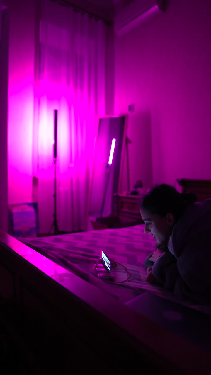 chica mirando el teléfono en el dormitorio rosa por la noche