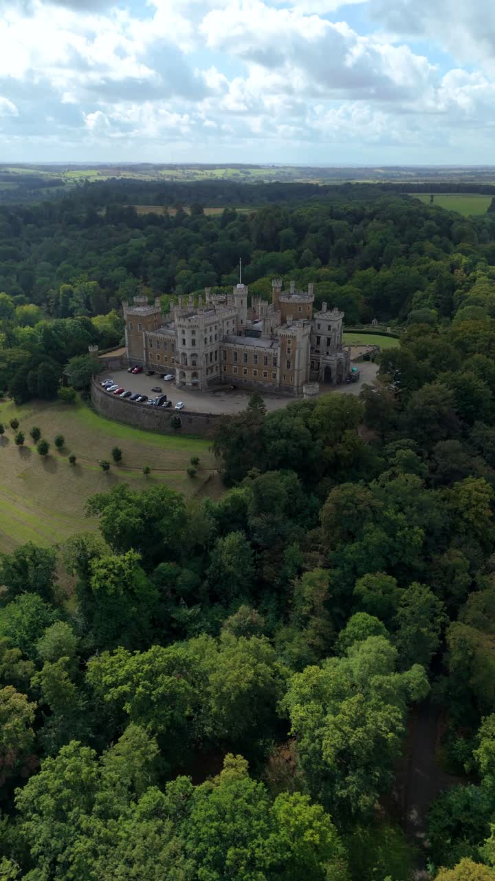 Vue aérienne cinématographique d’une forteresse médiévale s’élevant au-dessus de collines verdoyantes et d’un terrain rural dans la campagne des East Midlands, près de Grantham