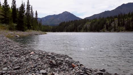 Peaceful-Yukon-wilderness-summertime-tranquil,-serene-and-remote-scene-of-Kluane-lake-waters-on-cloudy-blue-sunny-sky-day,-Canada,-handheld-pan-up