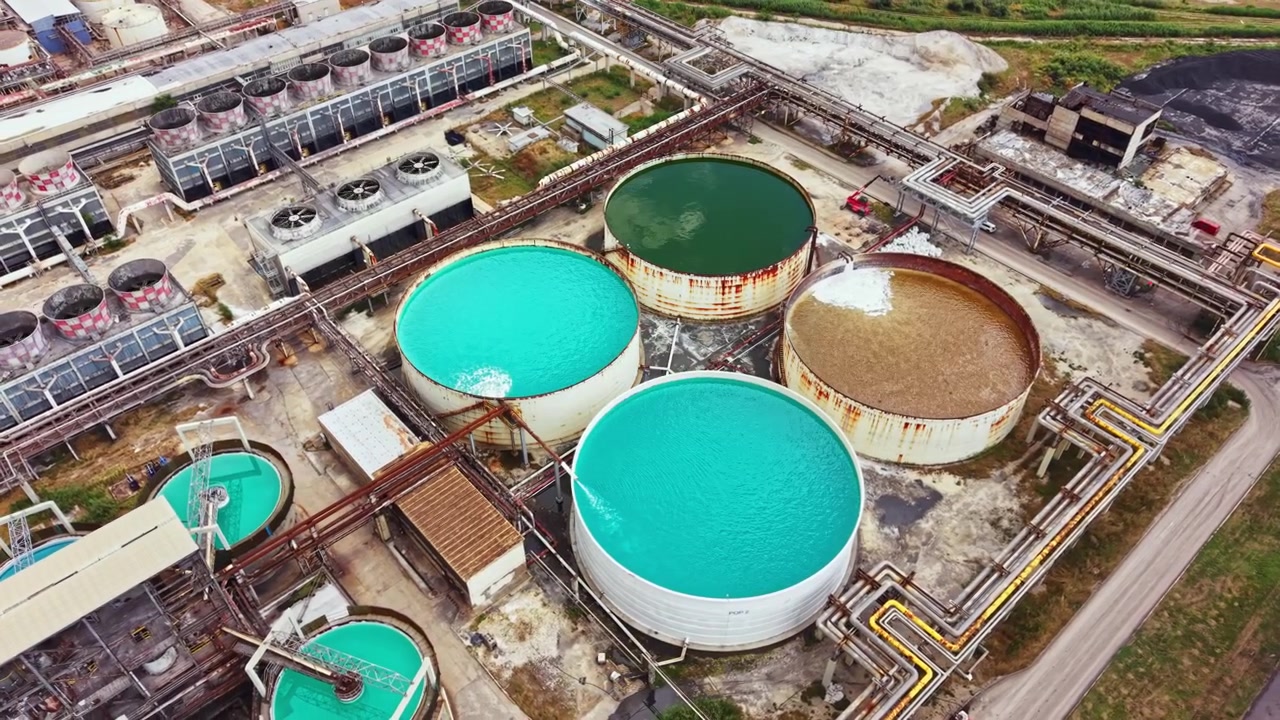 Industrial site with large tanks used for water treatment located in an urban area with pipes and machinery visible in the scene