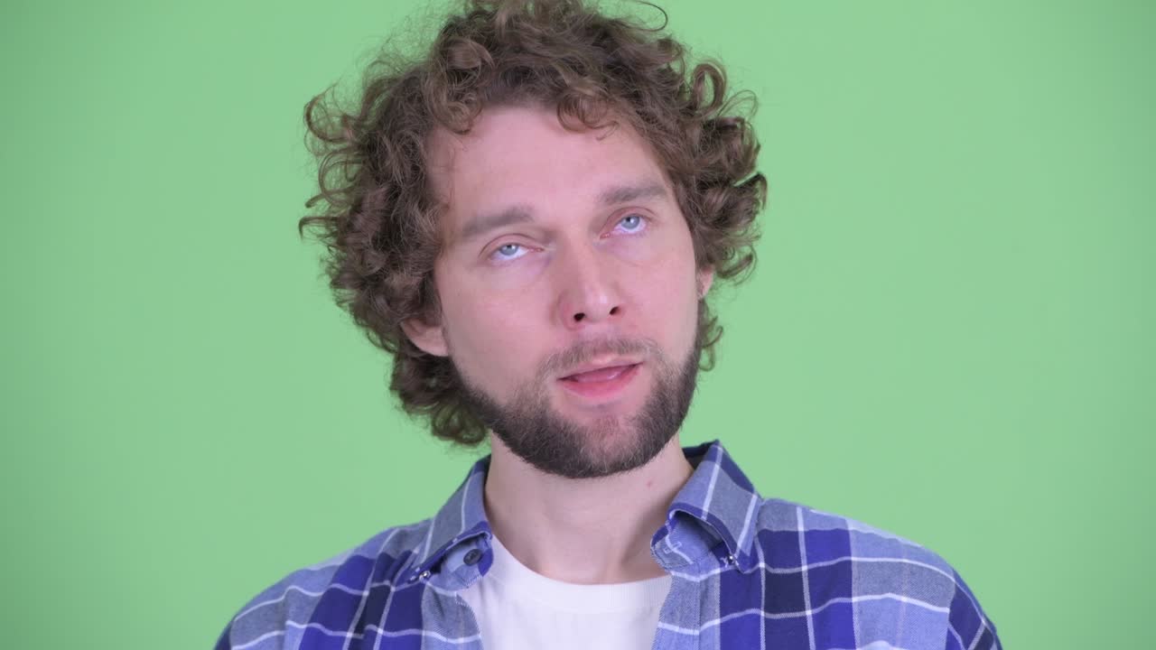 un joven guapo, barbudo y hipster con el cabello rizado.
