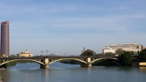 Coches-Circulando-Por-El-Puente-De-Triana-Con-La-Torre-De-Triana-Y-La-Torre-De-Sevilla-Al-Fondo-En-Sevilla,-España.