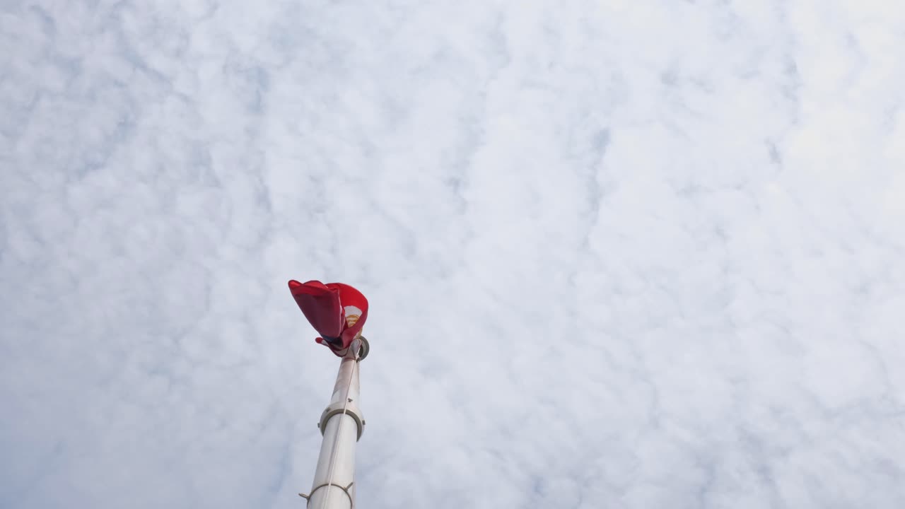 하늘이  ⁇ 은 구름으로 가득 차 있는 동안 기둥  ⁇ 에서 볼 수 있는 강한 바람 이후 필리핀 국기가 떨어지고 있습니다.