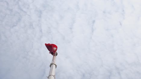 Die-Herabhängende-Philippinische-Nationalflagge-Nach-Einem-Starken-Wind,-Der-Unter-Der-Stange-Zu-Sehen-Ist,-Während-Der-Himmel-Mit-Flauschigen-Wolken-Gefüllt-Ist