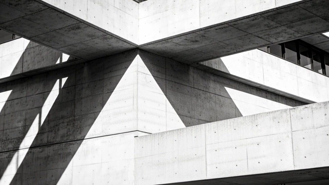 Reaching hand moving across foreground at modern concrete corner, revealing triangular shadows
