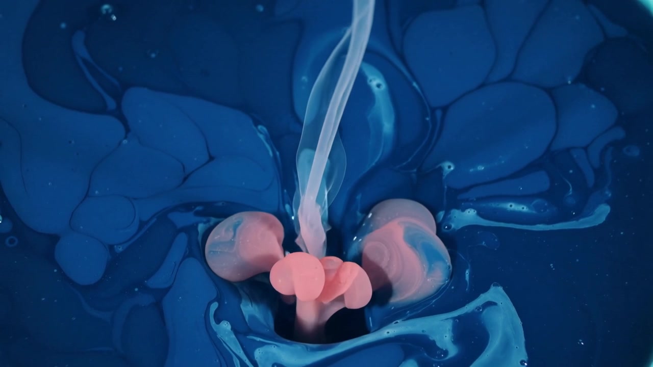 Versando un sottile flusso pallido che forma lobi rosa pallido in un vassoio, mescolando pigmenti in un liquido blu scuro.